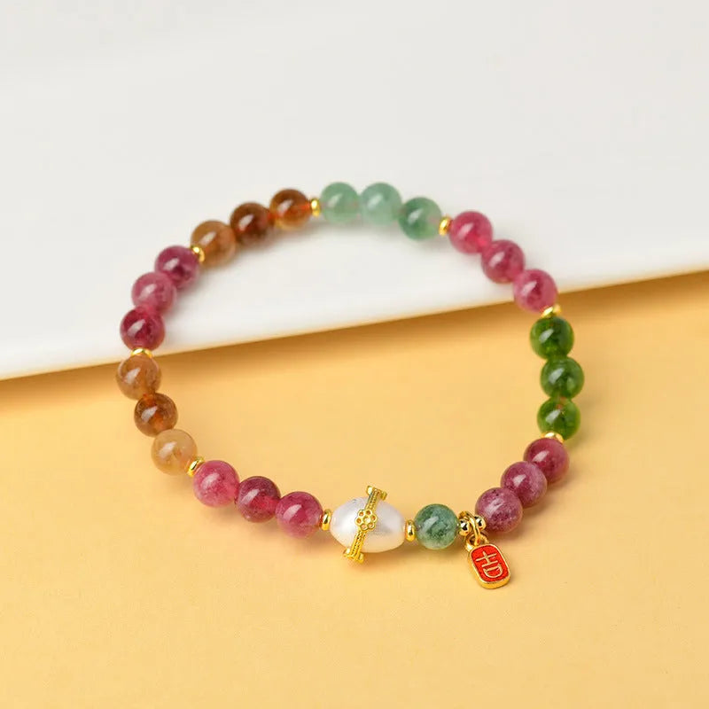 Close-up of a chalcedony bracelet with geometric 6.5mm beads in a tourmaline colour on a wrist.