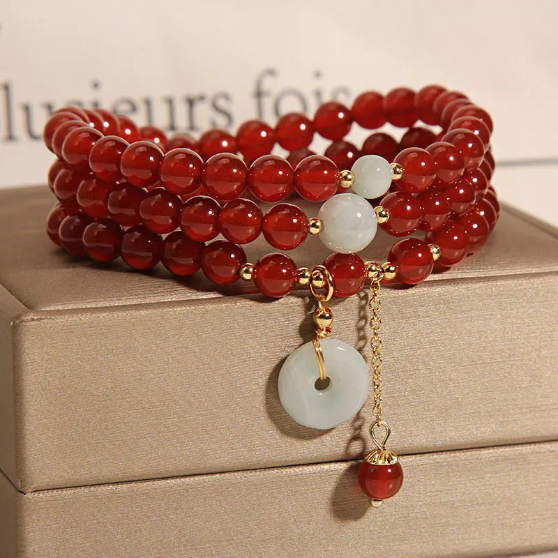 Women's multi-layer red agate crystal bracelet with adjustable closure on a wrist.