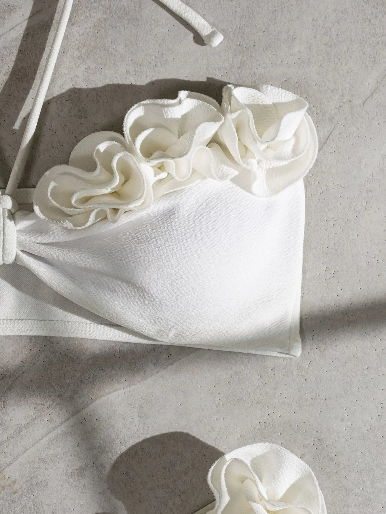 White halter neck bikini set with lace-up back and three-dimensional floral pattern on briefs.