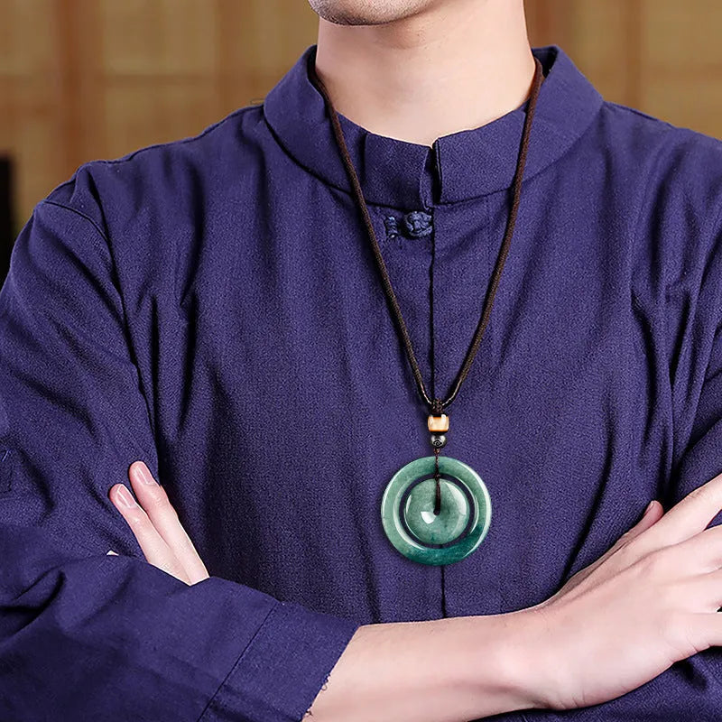 Emerald green jade pendant with carved national style design on a necklace stand