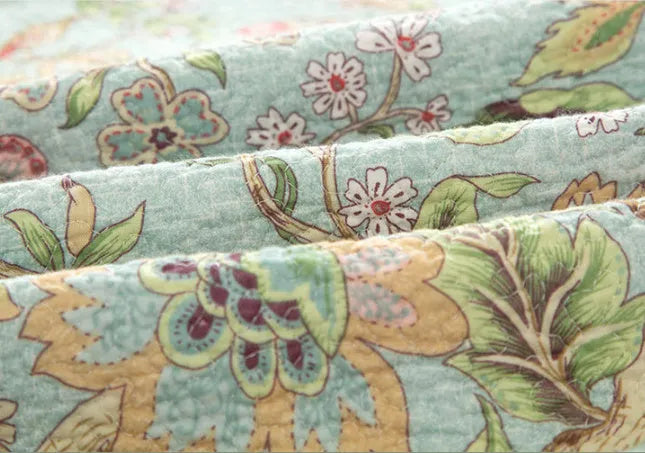 Blue American floral and bird pattern quilted cotton bedspread draped on a double bed