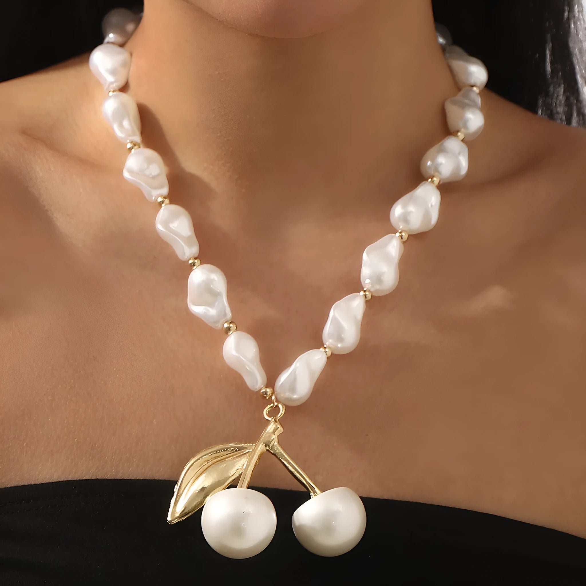Gold-tone adjustable necklace with imitation pearls and cherry fruit pendants on a white background.