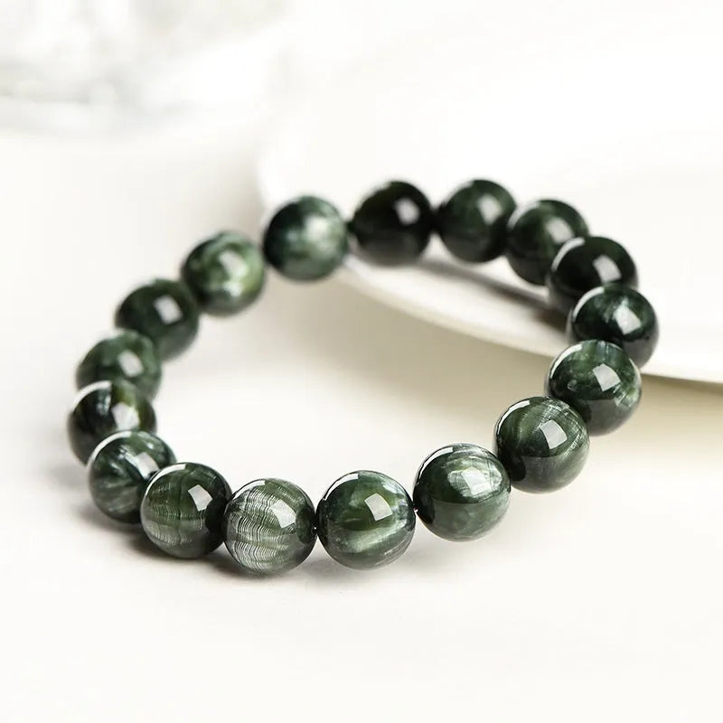 Close-up of a green dragon crystal bead bracelet with round geometry beads and a Ruyi charm.