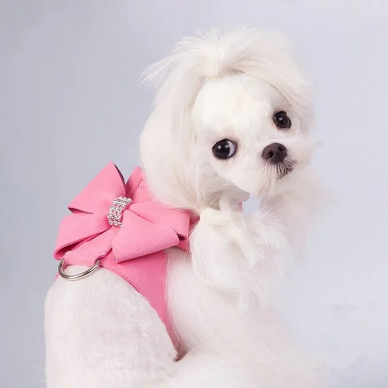 A pink microfiber dog harness with a bowknot on the chest strap, shown on a small dog.