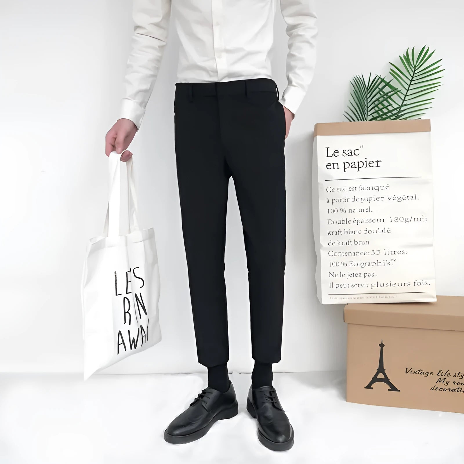 Man wearing black straight-leg cotton trousers with a drawstring waist, styled casually.