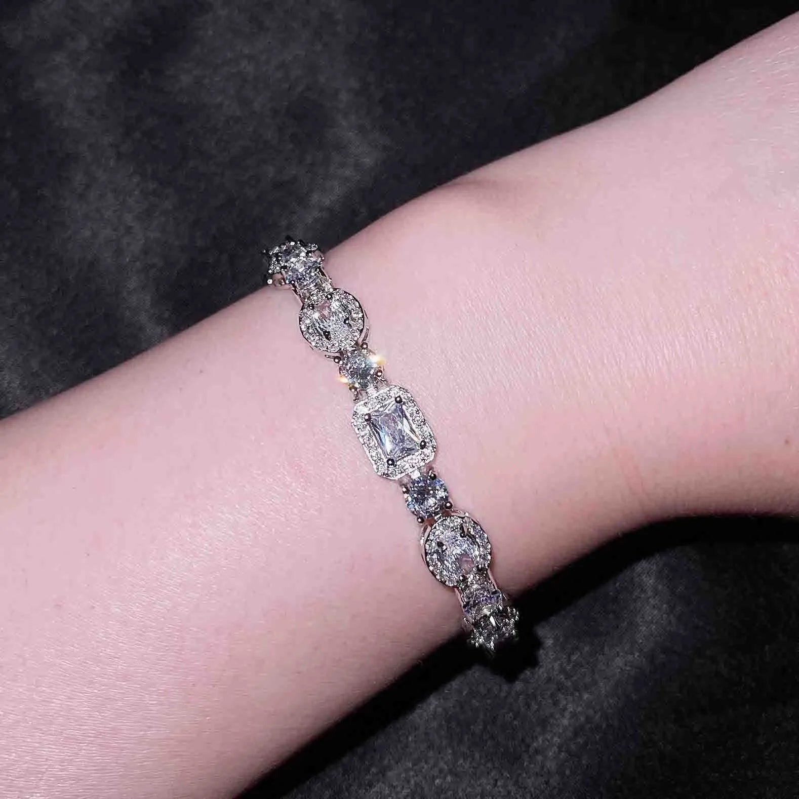 Women's geometric silver bracelet with adjustable chain and sparkling zircon stone on a wrist.