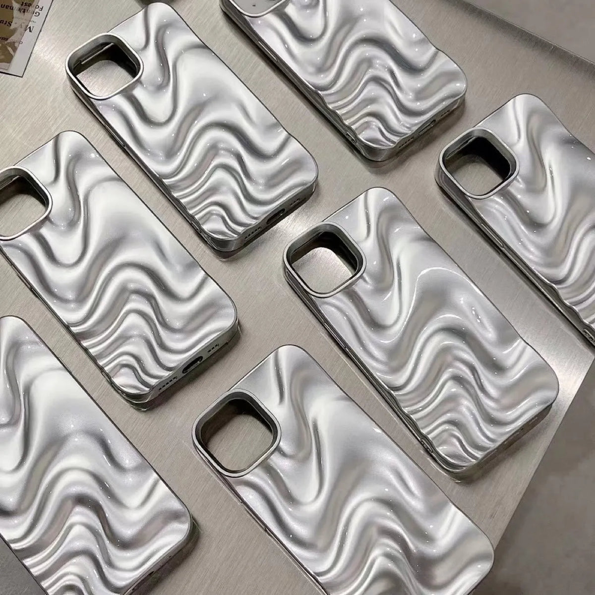 Three-dimensional pleated water ripple TPU phone case for iPhone 14 in glossy silver, showing textured back and edge coverage