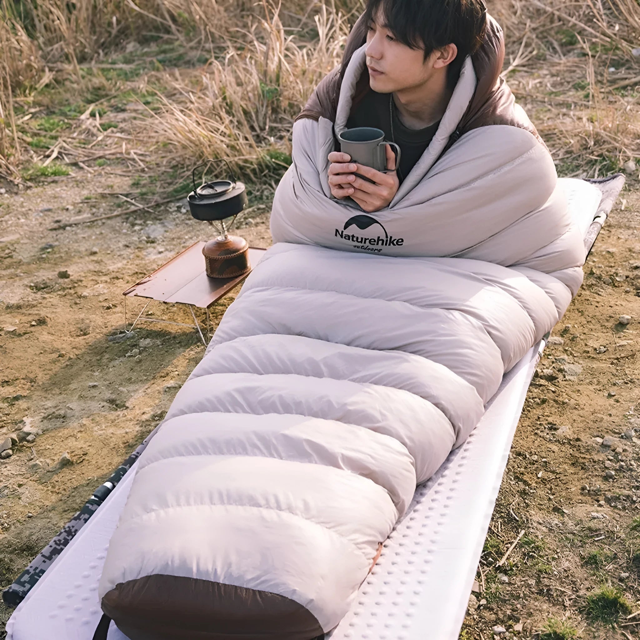 Adult mummy-style sleeping bag with goose down filler, shown with its storage bag