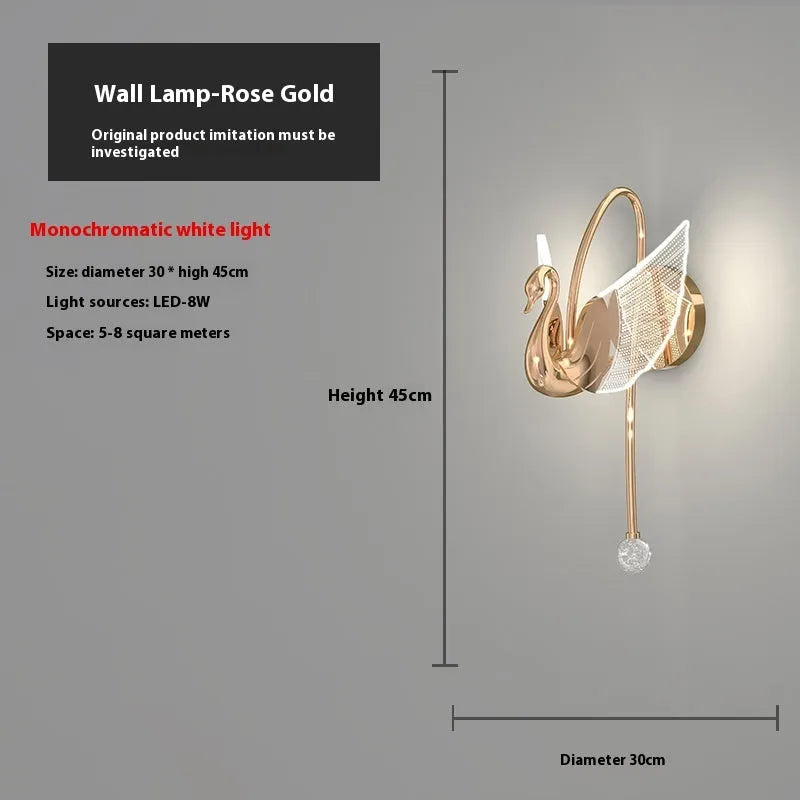 Gold modern swan-shaped wall lamp with acrylic shade mounted beside a bed.