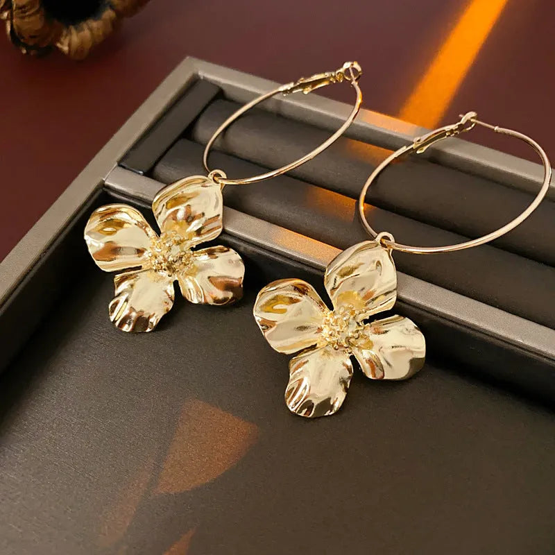 A pair of vintage-style metal earrings with a combined floral and geometric shape in a gold electroplated finish.