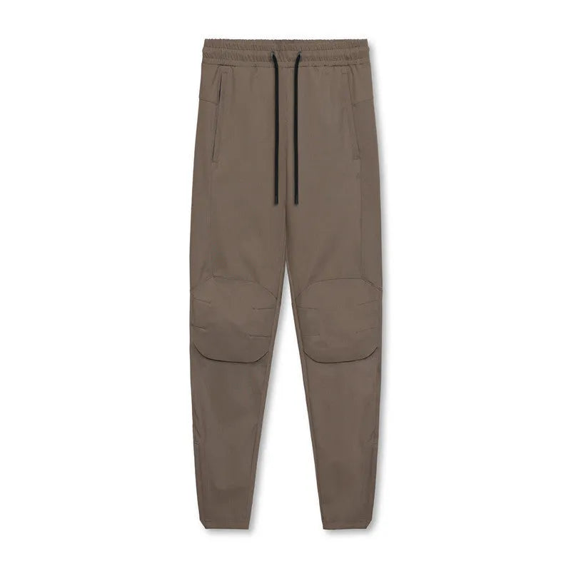 Men's grey loose-fit fitness trousers with ankle ties, made from quick-drying polyester fabric.