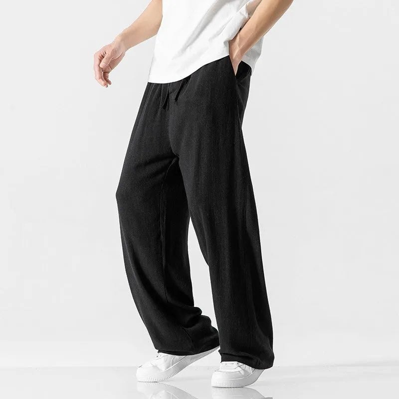 Man wearing beige loose-fit cropped straight-leg trousers made from bamboo fibre with a drawstring waist.
