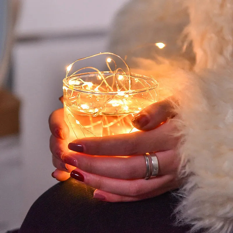 LED copper wire light string with warm white floral-shaped lamps on a dark background