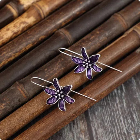 A pair of purple flower-shaped alloy earrings with an electroplated finish on a white background.