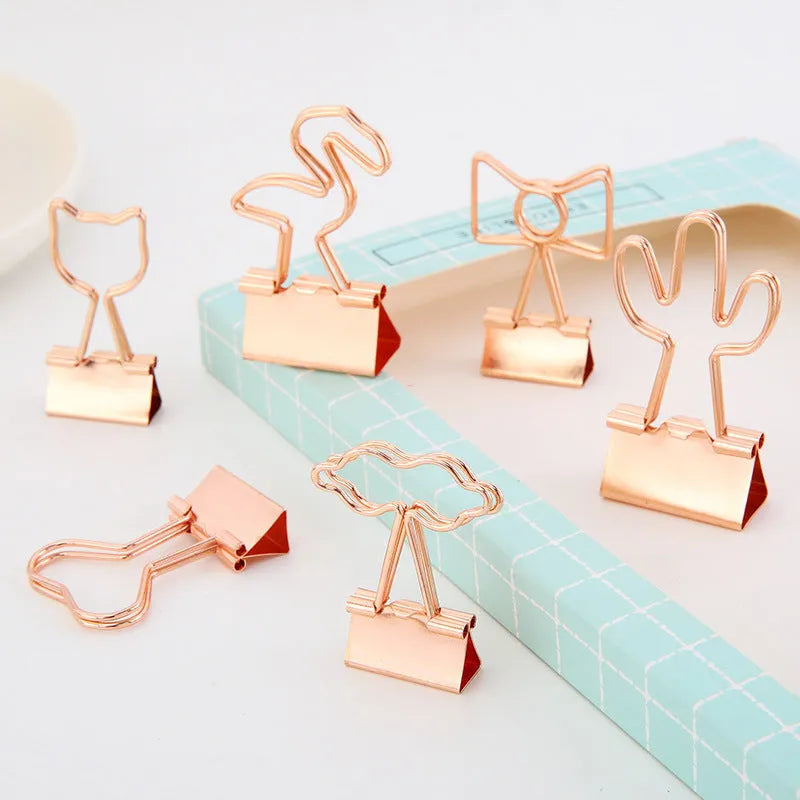 Gold metal alloy paper clip with decorative bow shape top on white background.