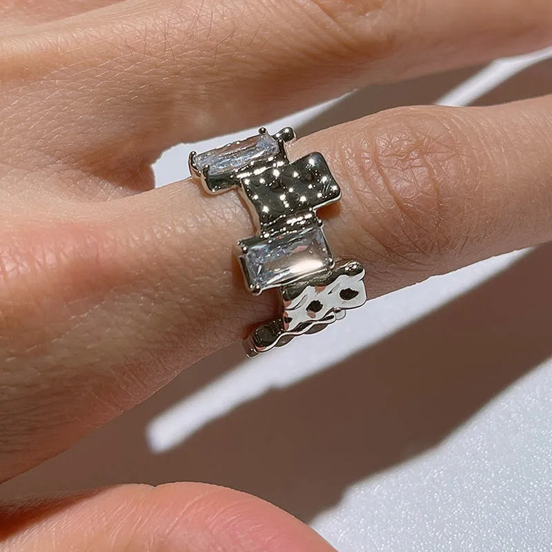 Silver plated open ring with cross design and zircon crystals.
