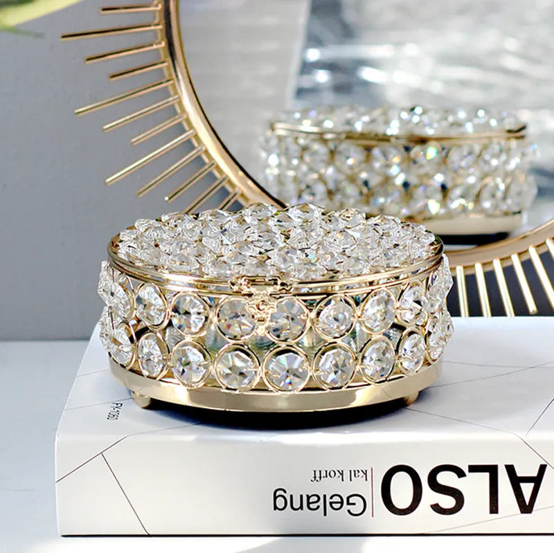 Transparent crystal glass jewelry storage box with a French gold-coloured metal frame on a table.