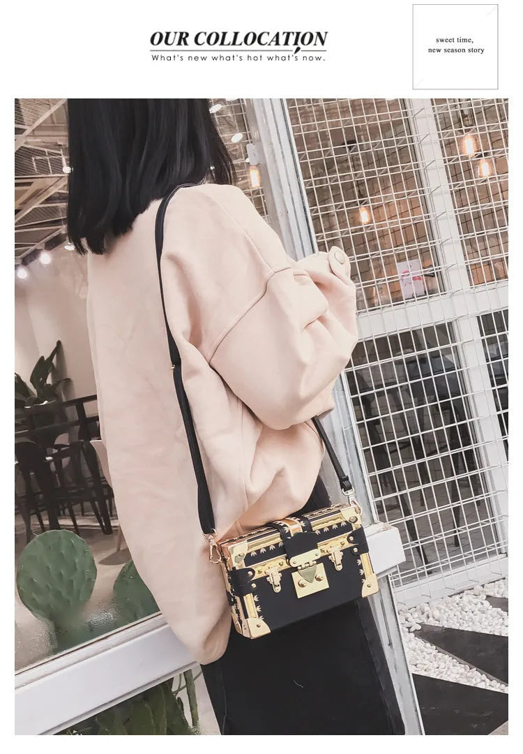 Hard-sided black women's shoulder bag with a flap closure, adjustable strap, and decorative metal rivets.
