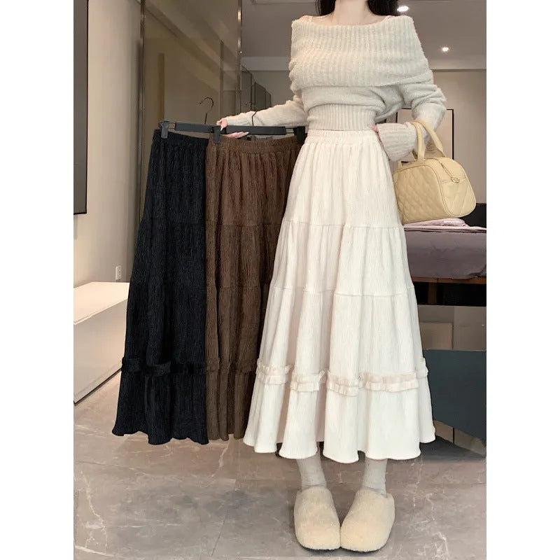 A woman wearing a beige corduroy A-line midi skirt with an elasticated waistband.