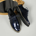 Women's black PU leather lace-up loafers with sequin details and a wedge heel, shown on a foot.