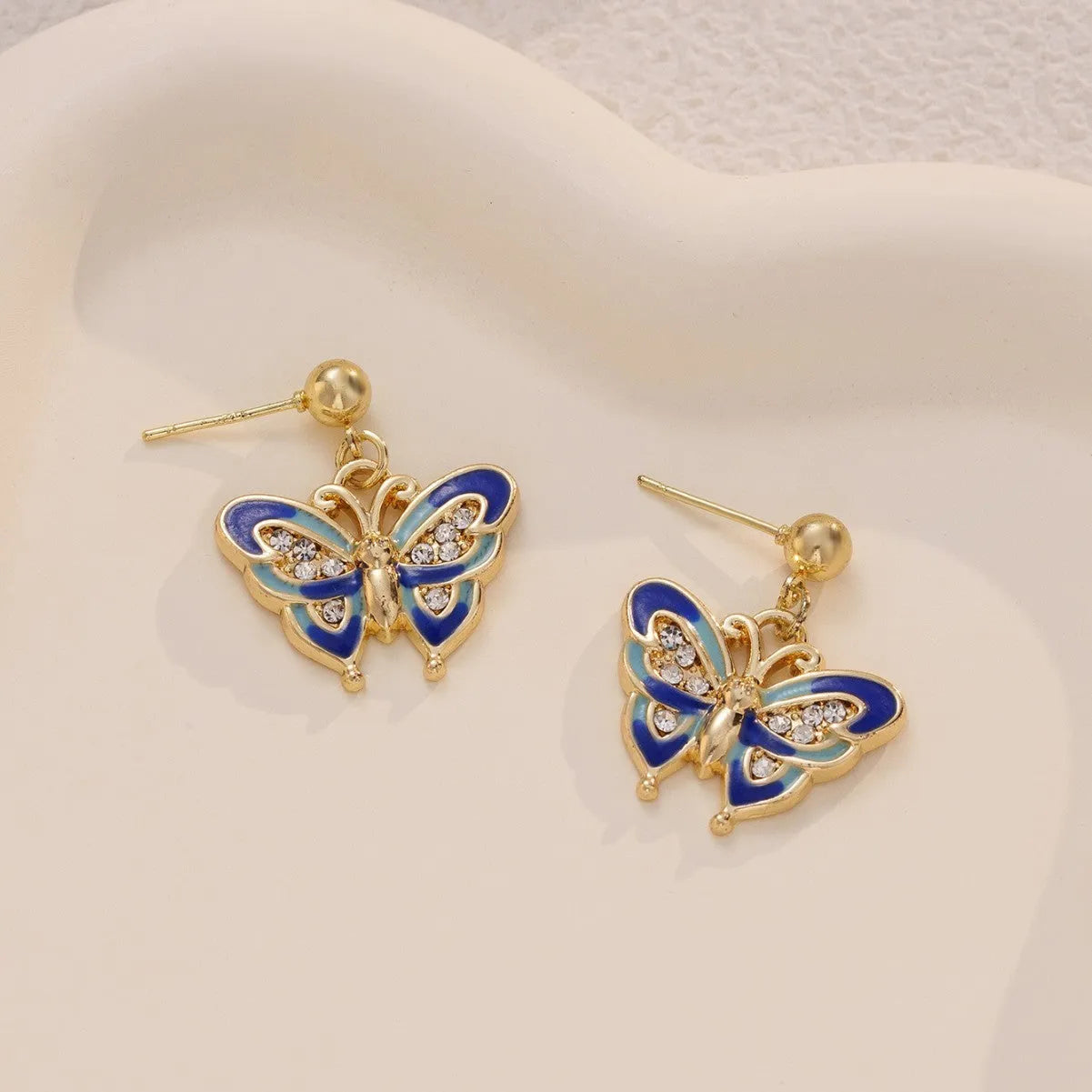 Dripping oil butterfly stud earrings in zinc alloy, classic style, colour O-4-17, on display