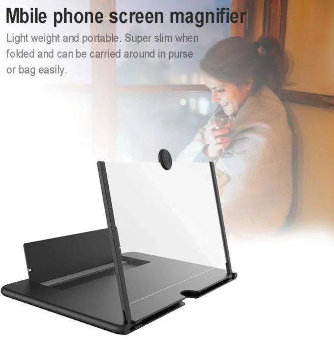 Folding mobile phone screen amplifier in black, with phone inserted, showing 3-4x magnification on a desk