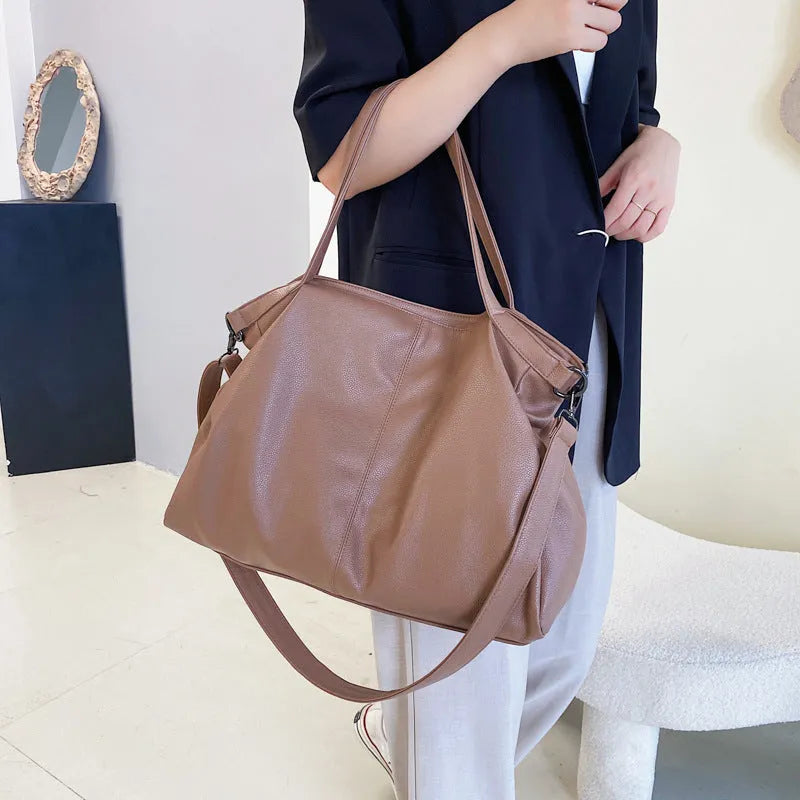 Large soft surface casual messenger bag in black showing horizontal shape and shoulder strap.