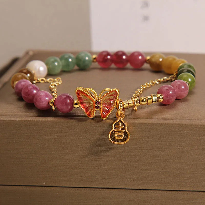 Close-up of a jade and tourmaline coloured agate bracelet with a butterfly-shaped gourd charm.