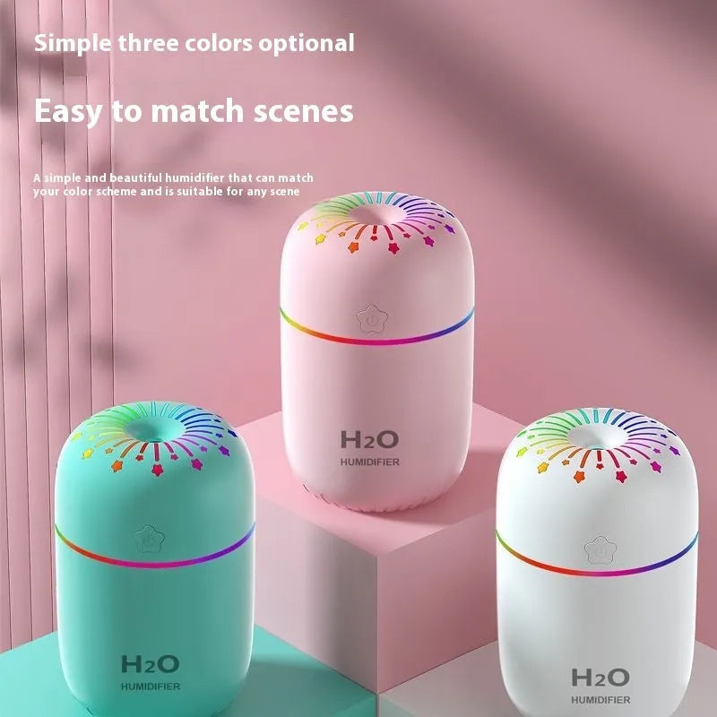 Compact white USB mini humidifier with water tank on a desk next to a laptop.
