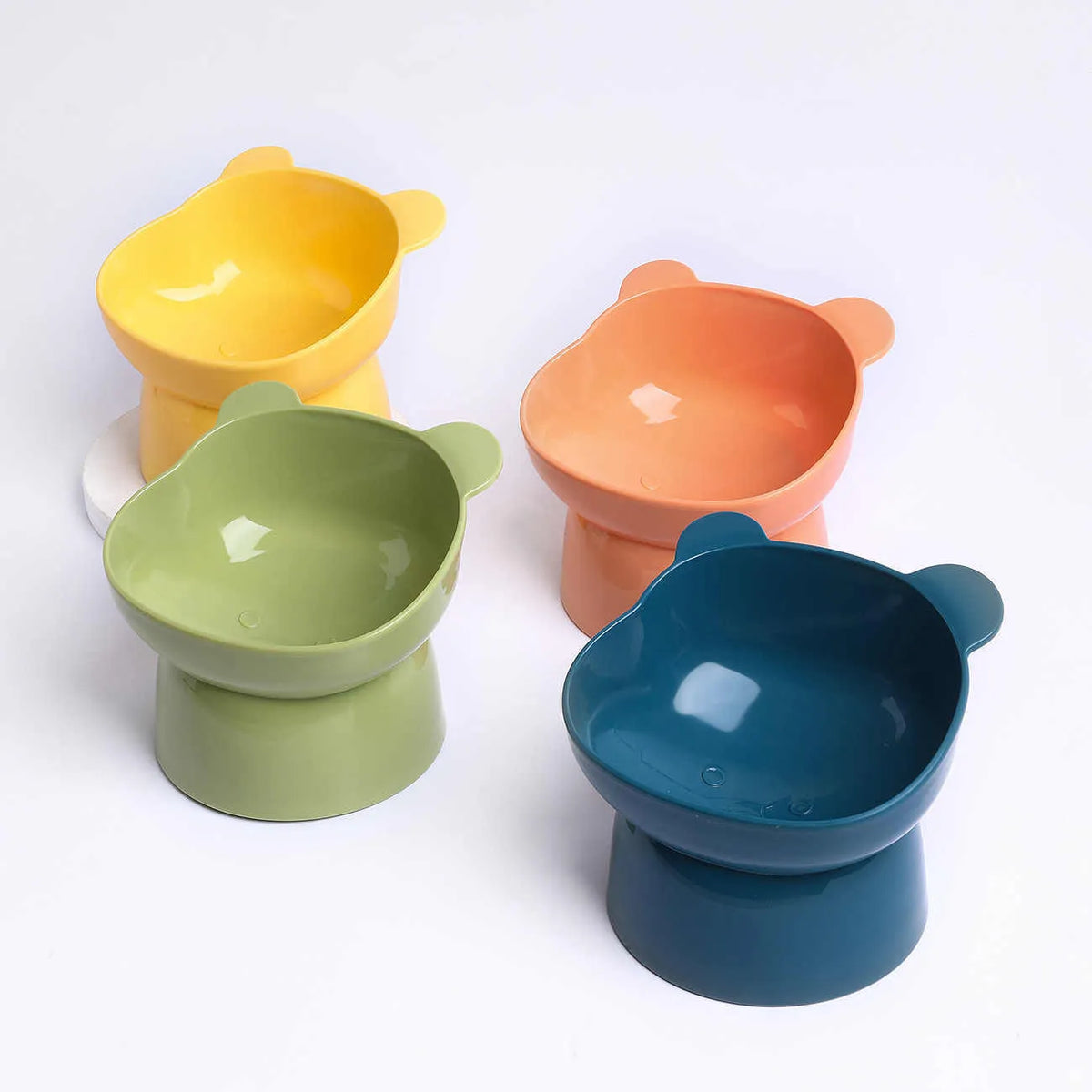 Oblique high foot pet bowl in PP for cats and dogs, shown in one of four colours: rouge pink, deep sea blue, lemon yellow or green grass green.