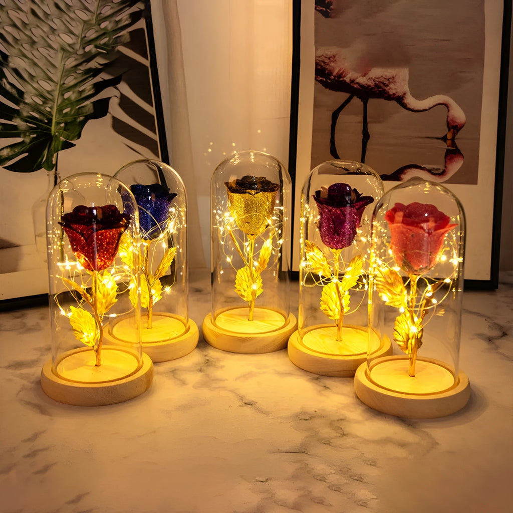 Red eternal rose with warm white LED lights under a glass dome on a table.