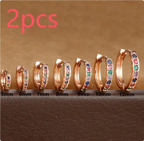 Circle-shaped perforated stud earrings in gold, rose gold, and silver colours on a white background.
