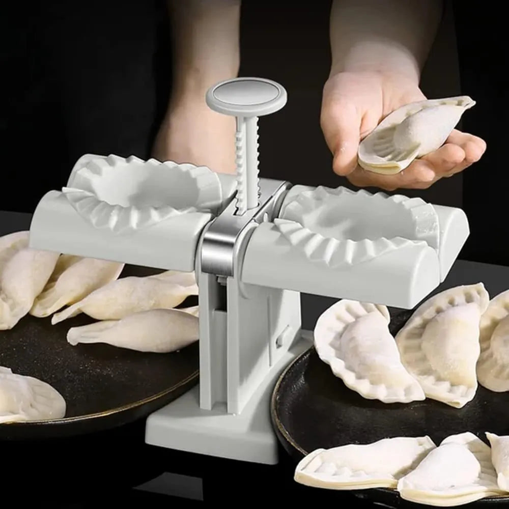 White double-head manual dumpling maker with anti-slip rubber base on a kitchen counter.