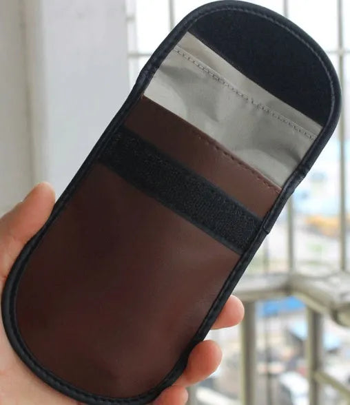 Black plain microfiber faraday cage bag for blocking RFID and phone signals, shown with a key fob inside.