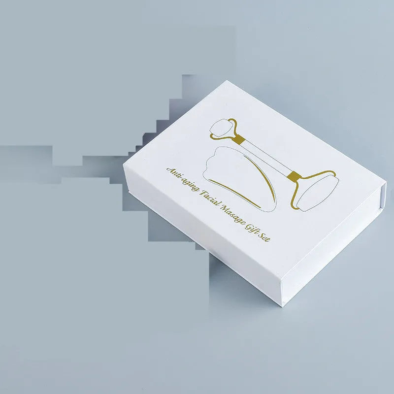 White jade double-headed facial roller and gua sha board set on a plain background.