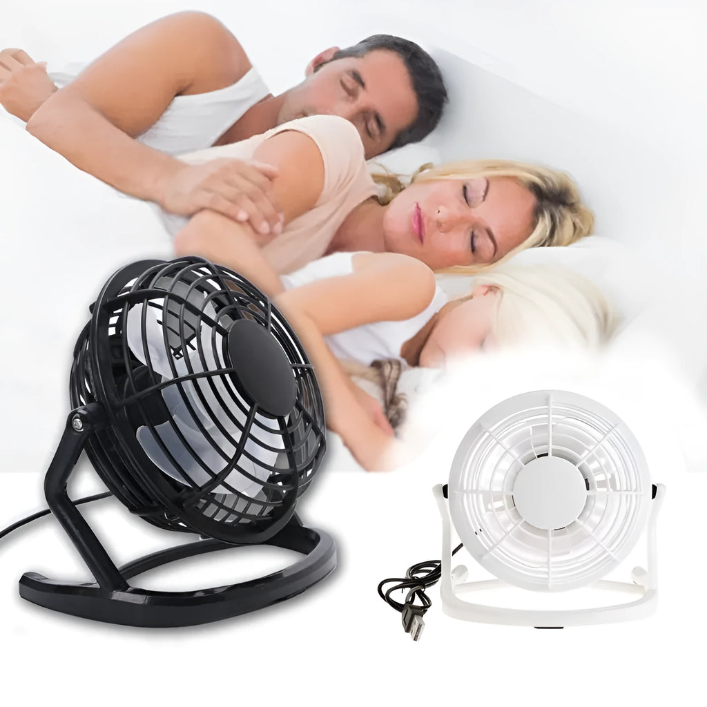 Small black and white USB desktop fan with adjustable stand on a desk next to a laptop.