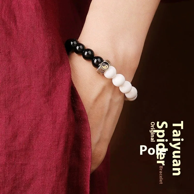 Black and white obsidian Tai Chi bracelet with geometric beads showing mantra inscriptions.