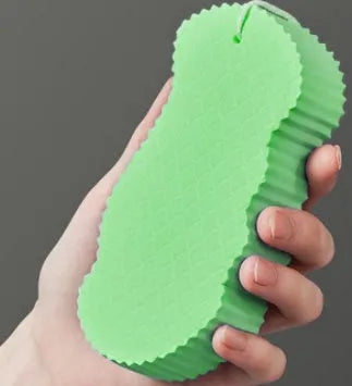 White 3D fish scale pattern bath sponge with hang loop on a bathroom background.