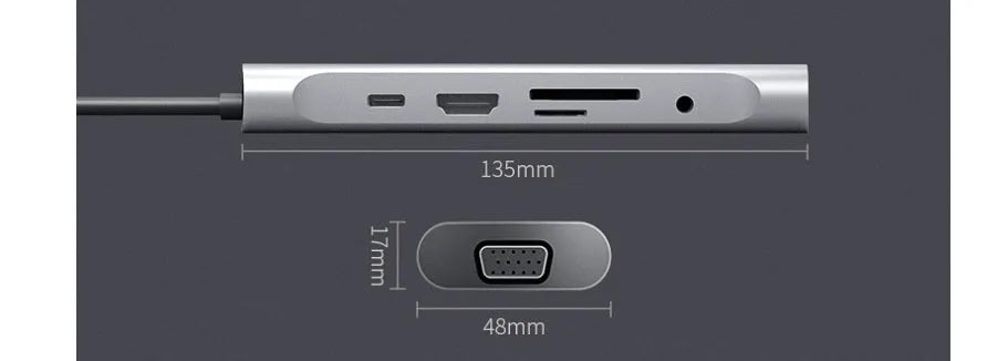 Grey aluminium USB-C docking station with HDMI, VGA, USB, and charging ports on a wooden desk.