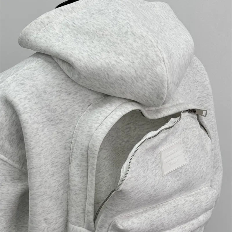 Man wearing a light gray hooded coat with a schoolbag design detail on the back.