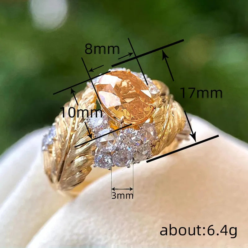 Gold-coloured embossed feather ring with geometric pattern and yellow zircon stones on a white background.
