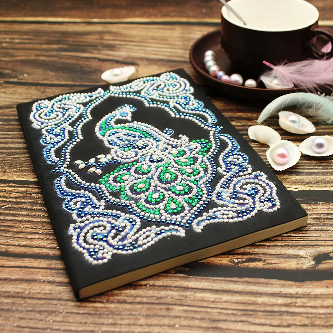 Peacock Beauty A5 diamond painting notebook with coloured resin drills on a black cover.
