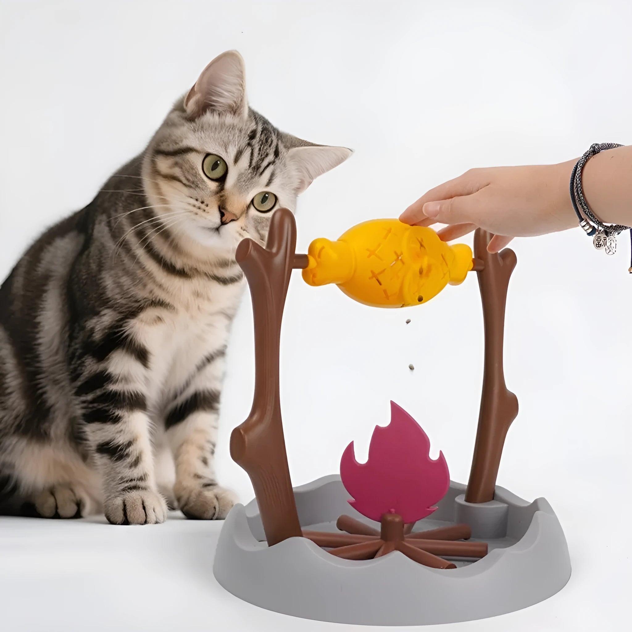 Cat playing with a colourful tumbling puzzle feeder toy that dispenses food.