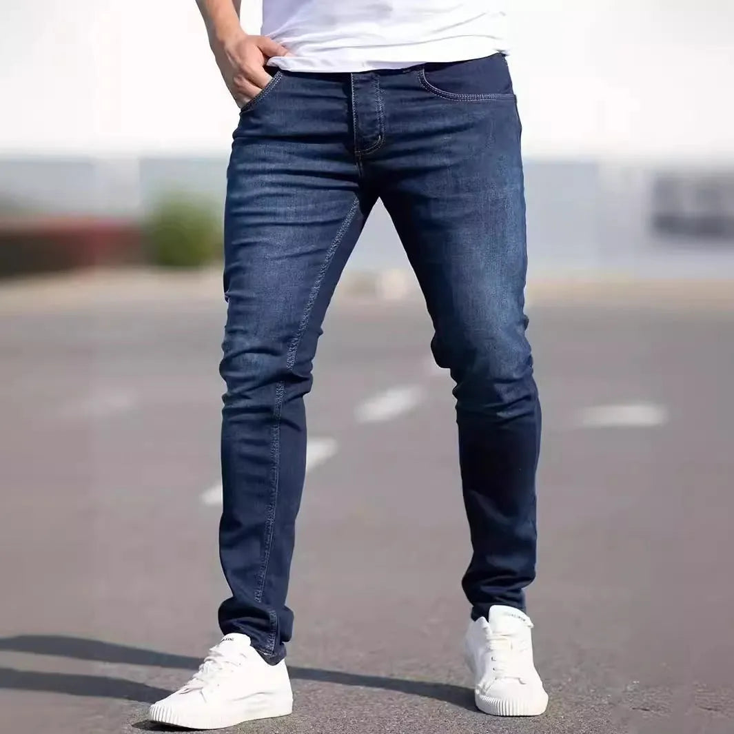 Men's dark blue skinny-fit cotton jeans with a mid-rise waist and zipper fly on a plain background.