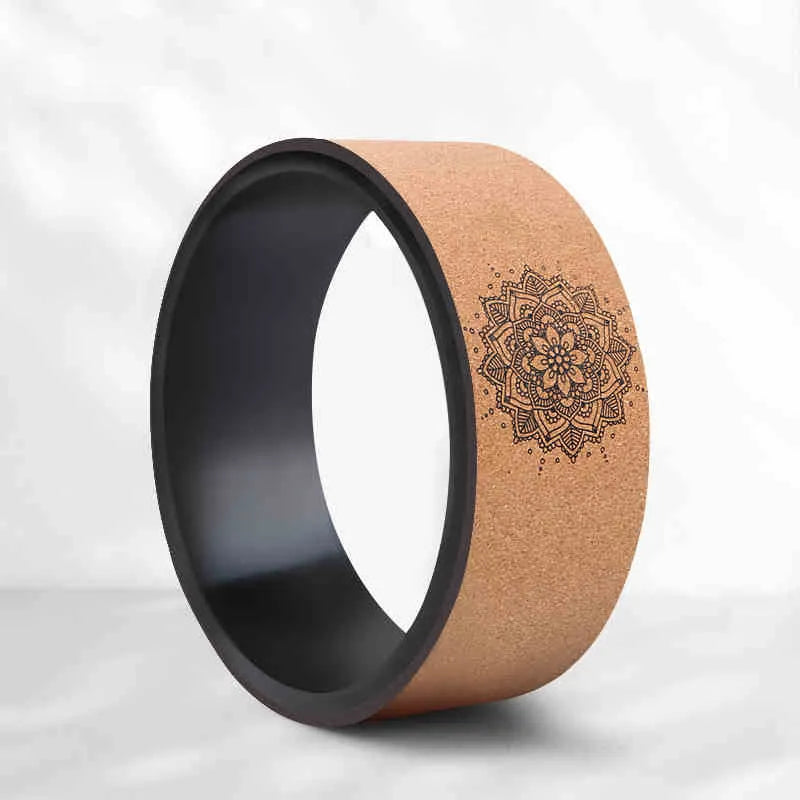 Brown cork yoga wheel with Mandala flower design on a wooden floor