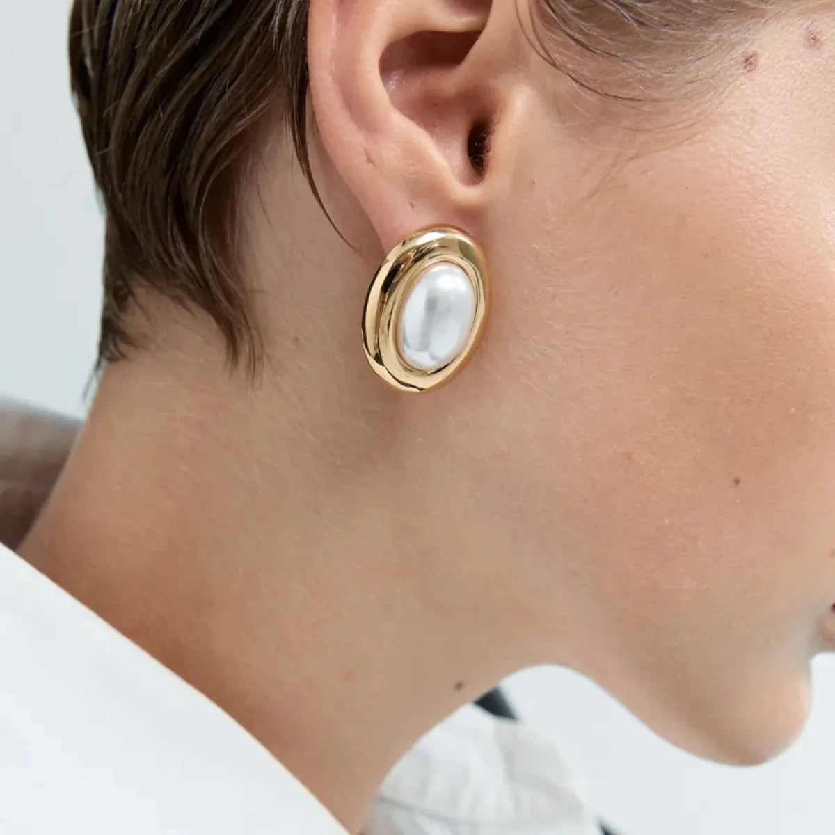 A pair of stainless steel stud earrings with a vintage pearl centre in a silver-tone finish.