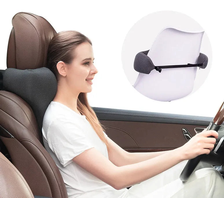 Dark grey memory foam car neck pillow resting on a car seat headrest.