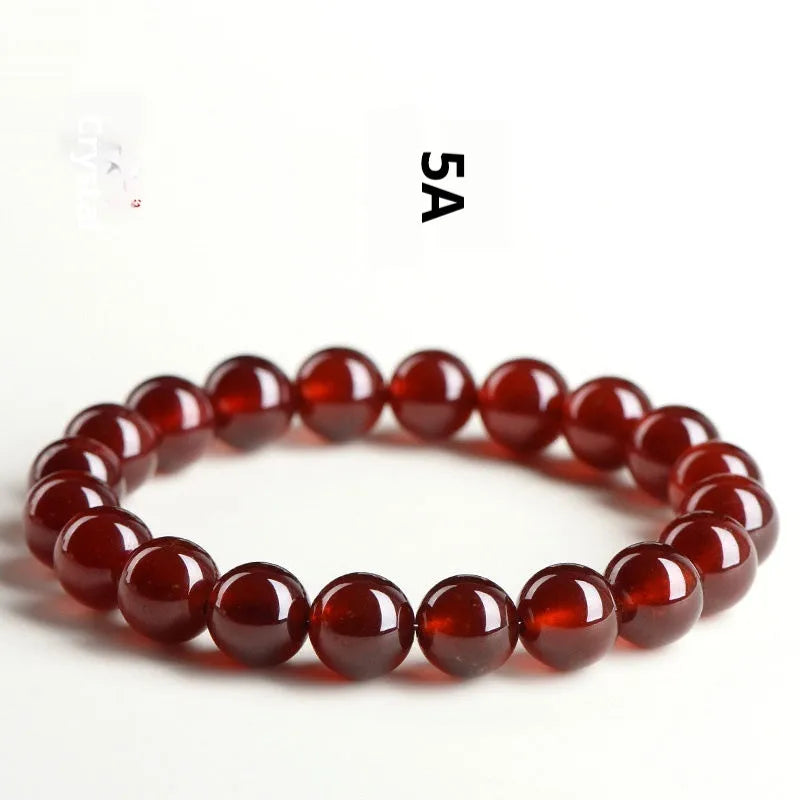 Natural Orange Red Garnet ball bead bracelet with a metal Ruyi charm on a white background.