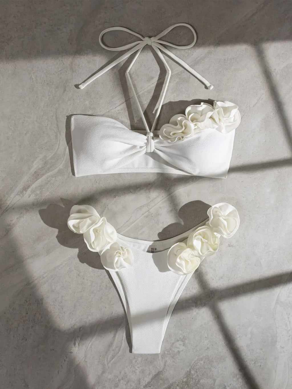 White halter neck bikini set with lace-up back and three-dimensional floral pattern on briefs.