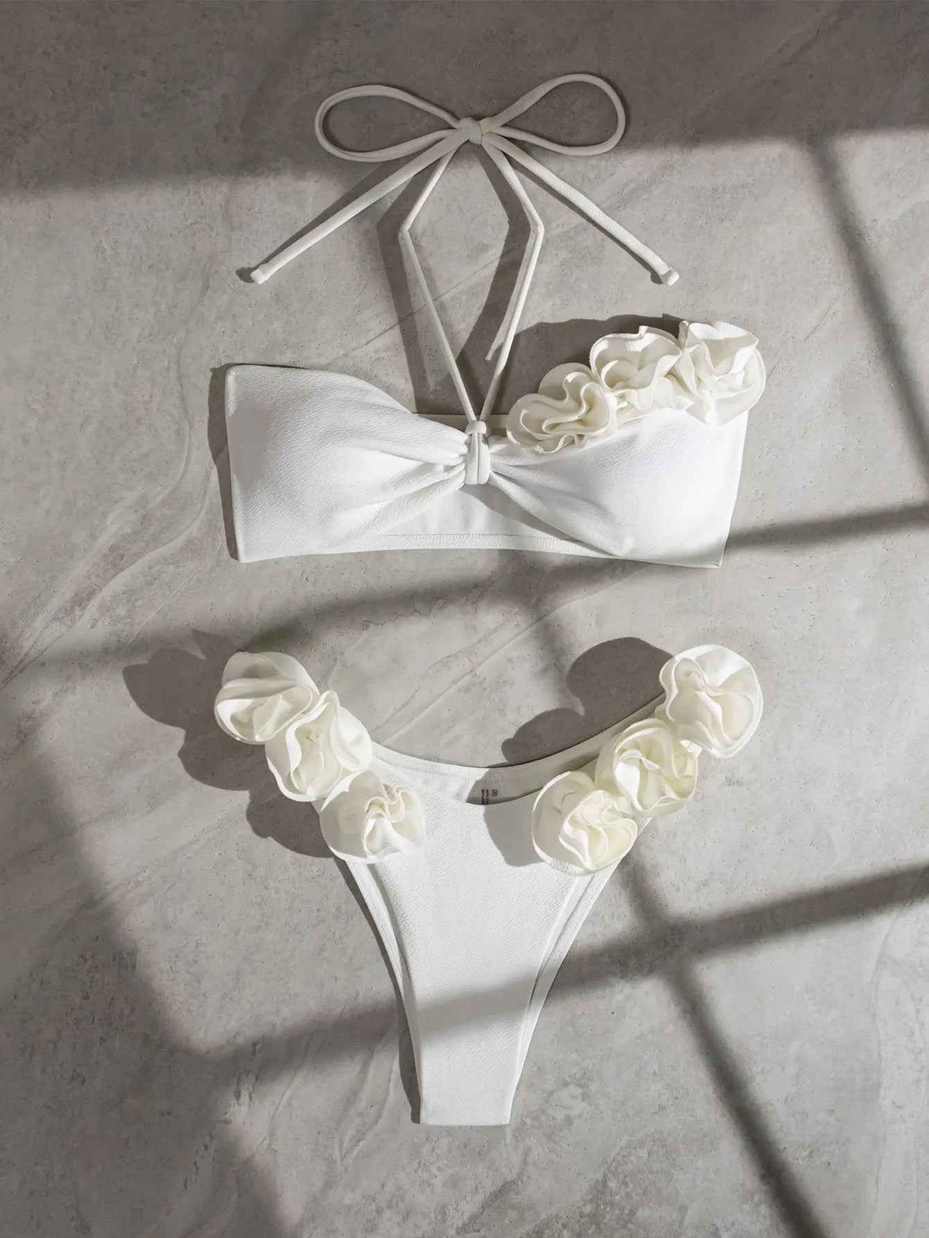 White halter neck bikini set with lace-up back and three-dimensional floral pattern on briefs.